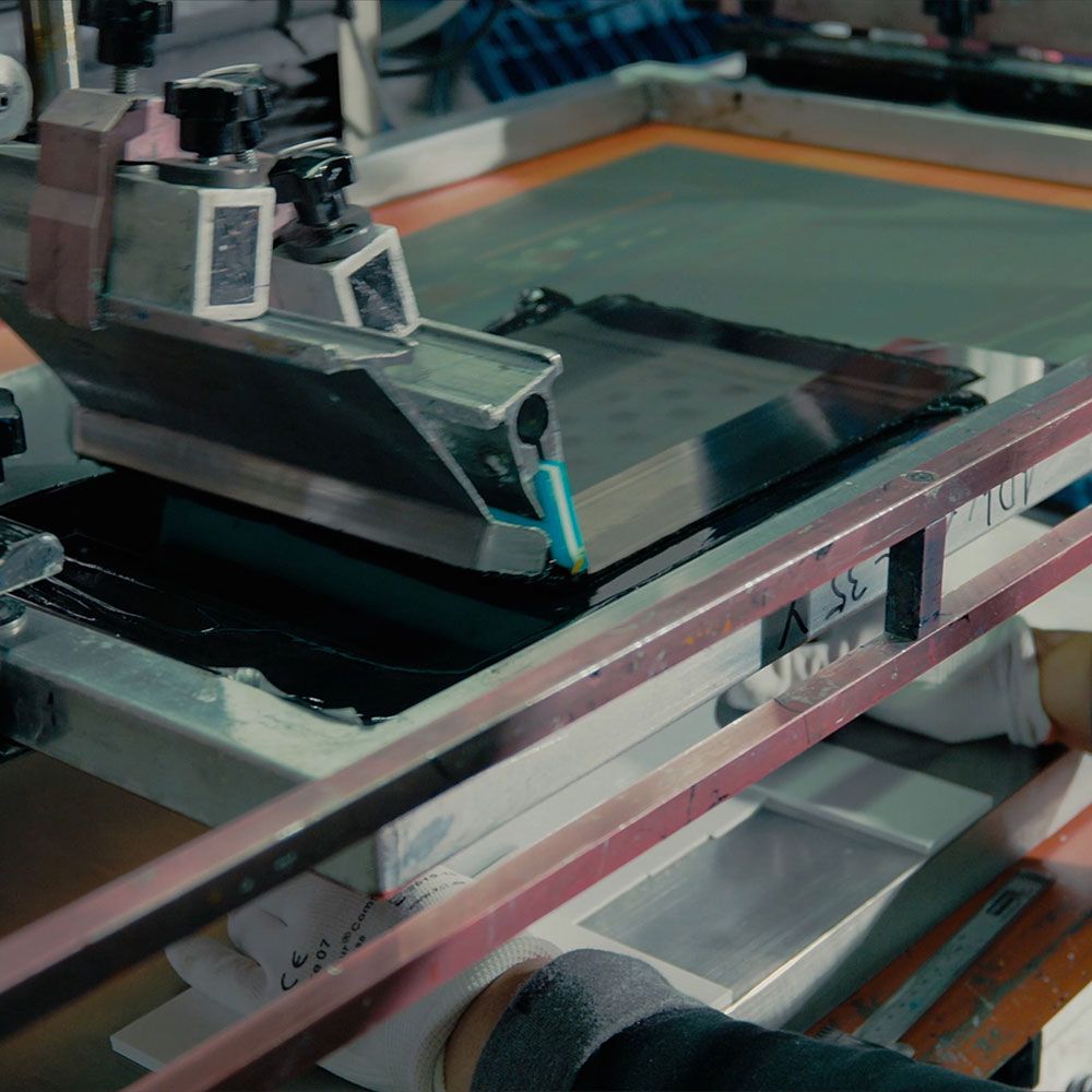 A technician inspects a metal enclosure with precisely drilled holes using a measuring tool.